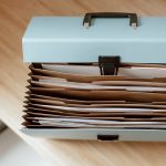 From above of briefcase for documents with papers placed on wooden table in daytime Mallette de documents avec des papiers vue de dessus placée sur une table en bois en plein jour