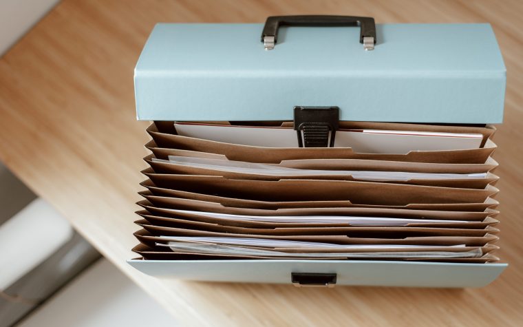 From above of briefcase for documents with papers placed on wooden table in daytime Mallette de documents avec des papiers vue de dessus placée sur une table en bois en plein jour