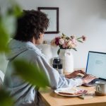 A woman working remotely at a desk with breakfast and coffee, showcasing a cozy home office setting. Une femme travaillant à distance à un bureau avec petit-déjeuner et café, mettant en avant un cadre de bureau à domicile confortable.