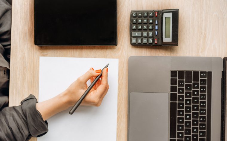 Personne calculant son salaire sur bureau professionnel