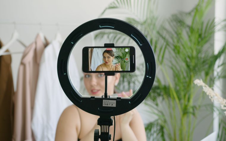 Femme créant du contenu vidéo avec smartphone et anneau lumineux