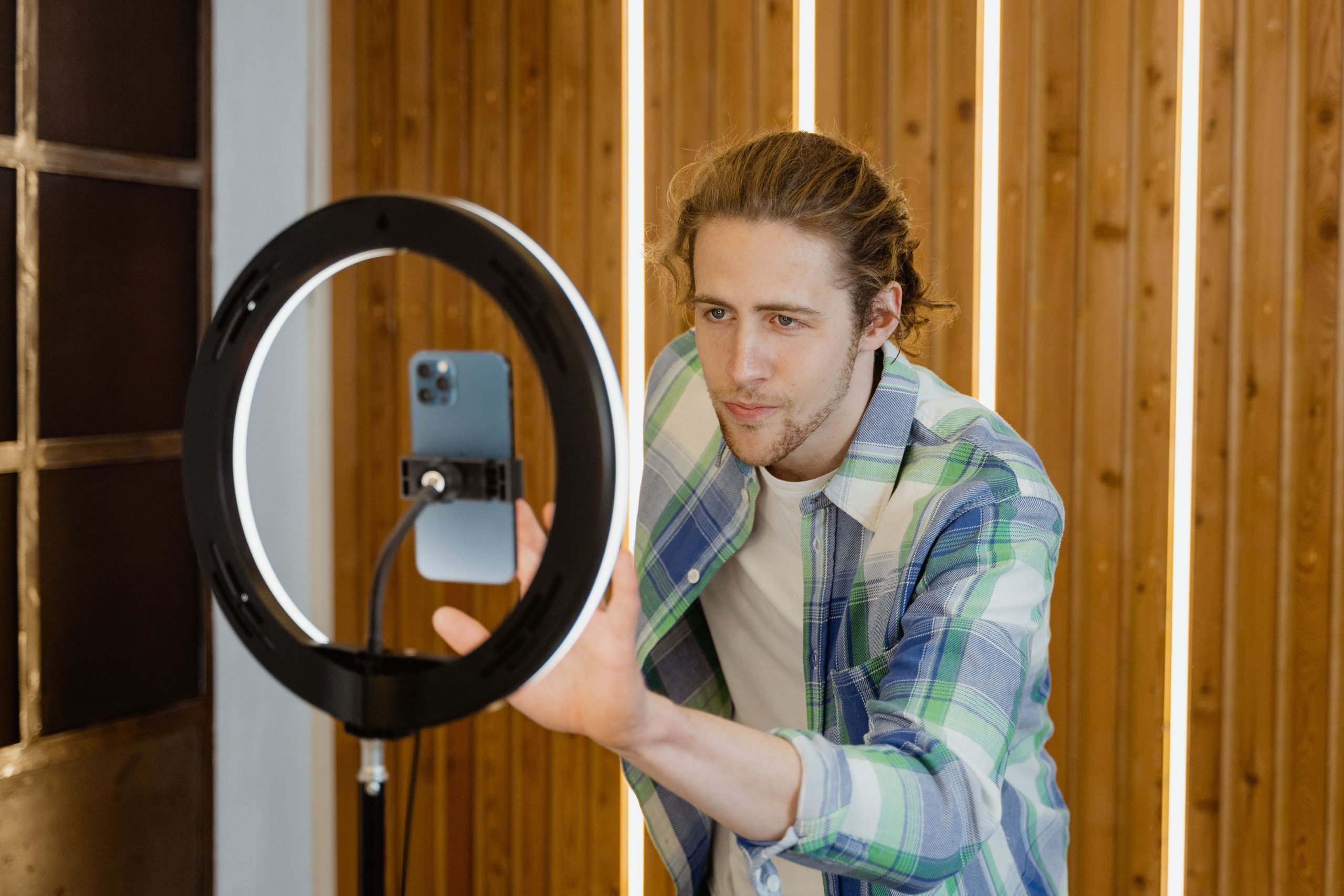 Jeune homme configurant smartphone et éclairage pour vidéo sociale