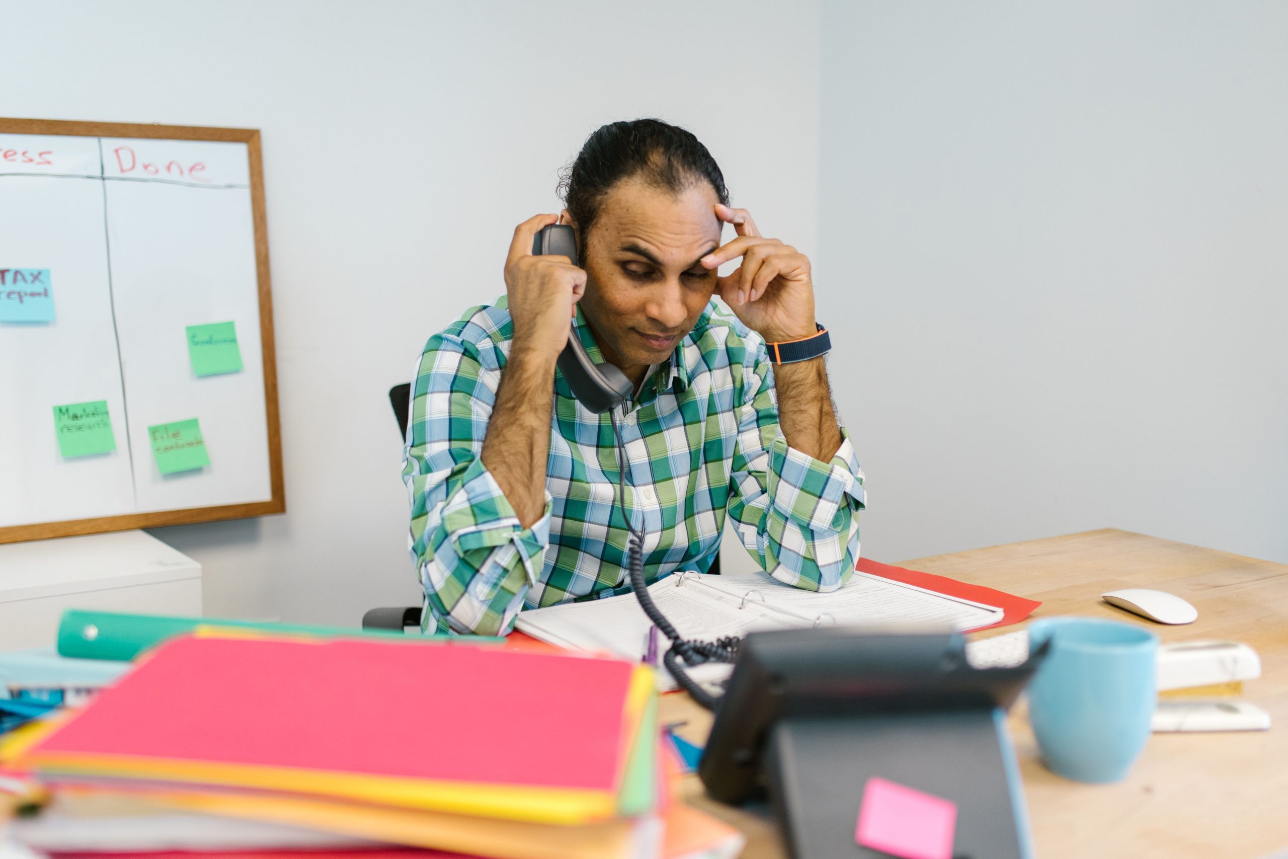 Homme d'affaires stressé au téléphone entouré de documents