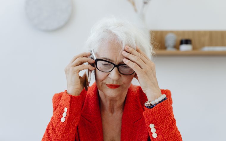 Femme senior stressée au téléphone en blazer rouge