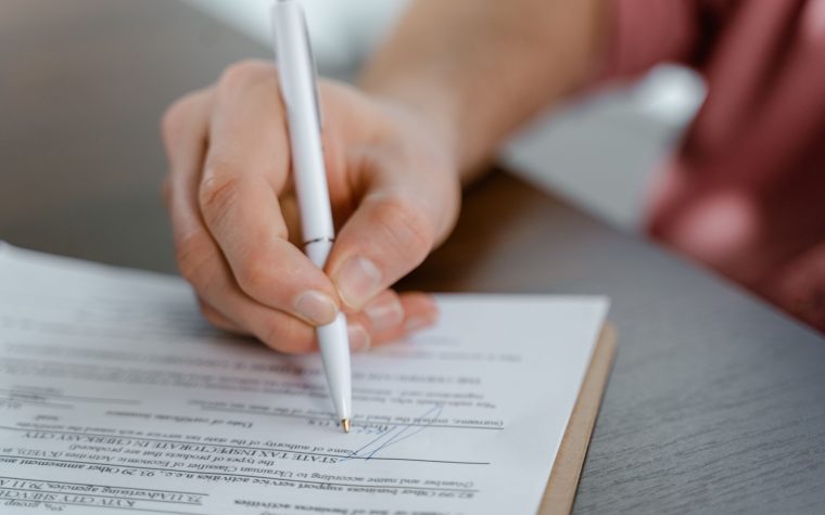 Main signant un document officiel au stylo