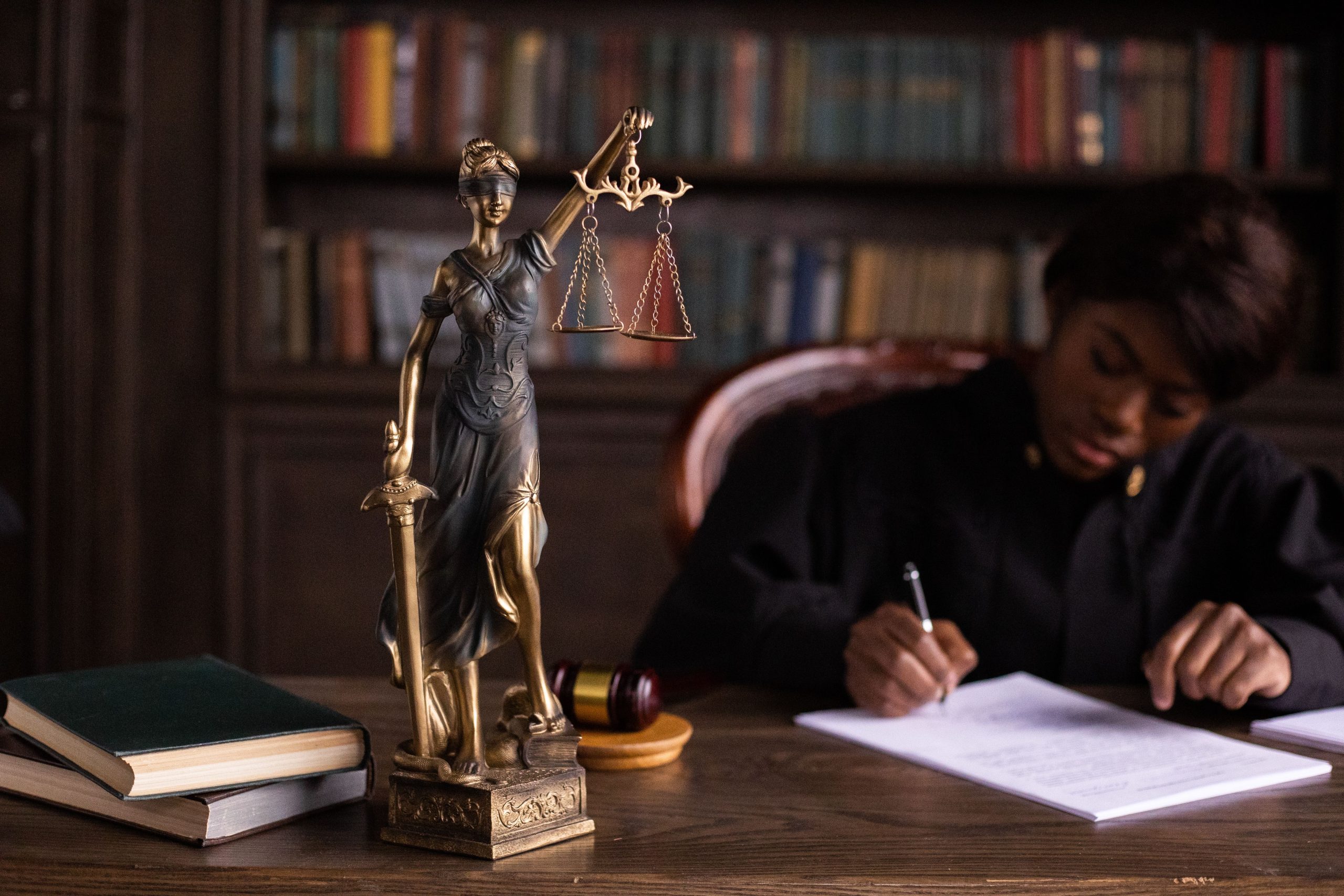 Juge écrivant sur documents près de statue Thémis