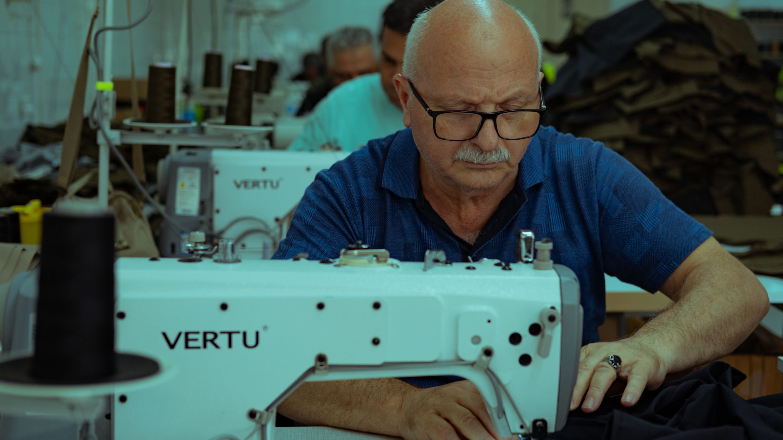 Couturière âgée cousant un vêtement à la machine