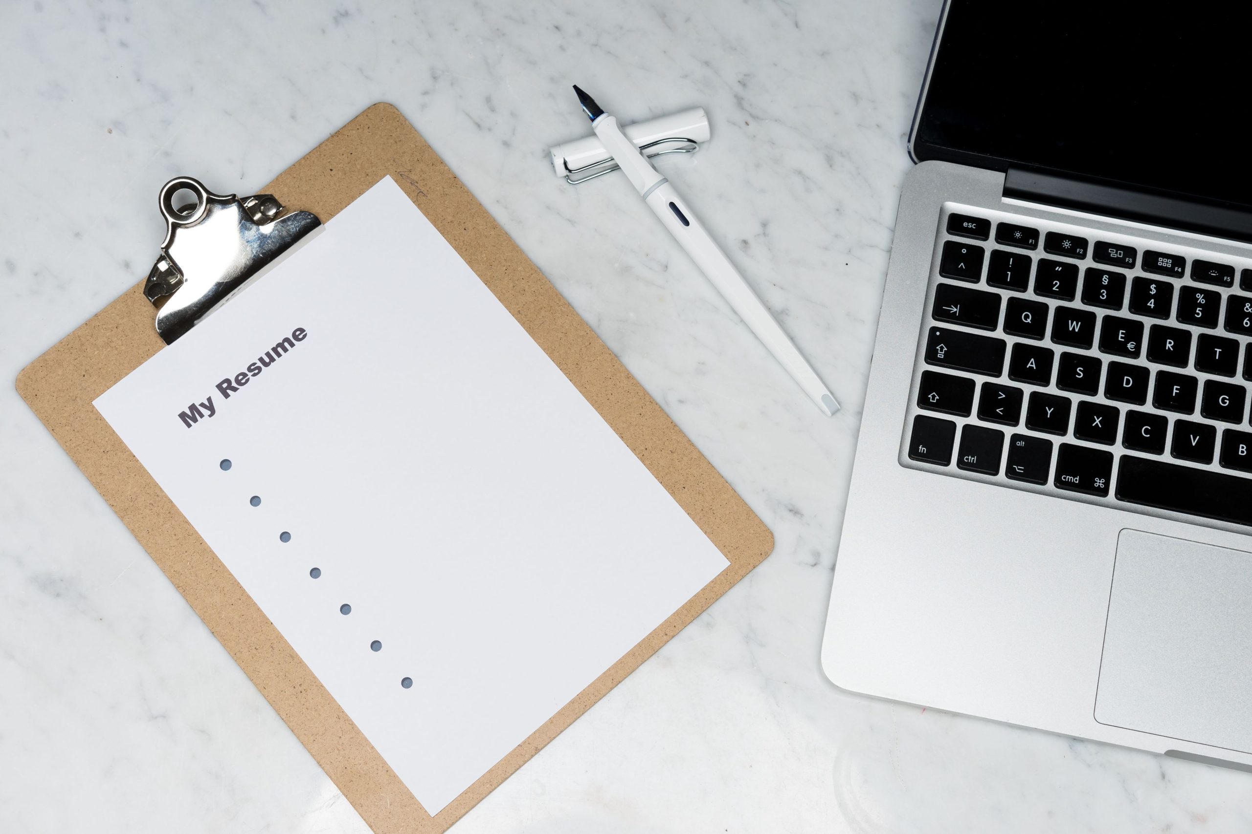 Presse-papiers avec CV, stylo et laptop marbre