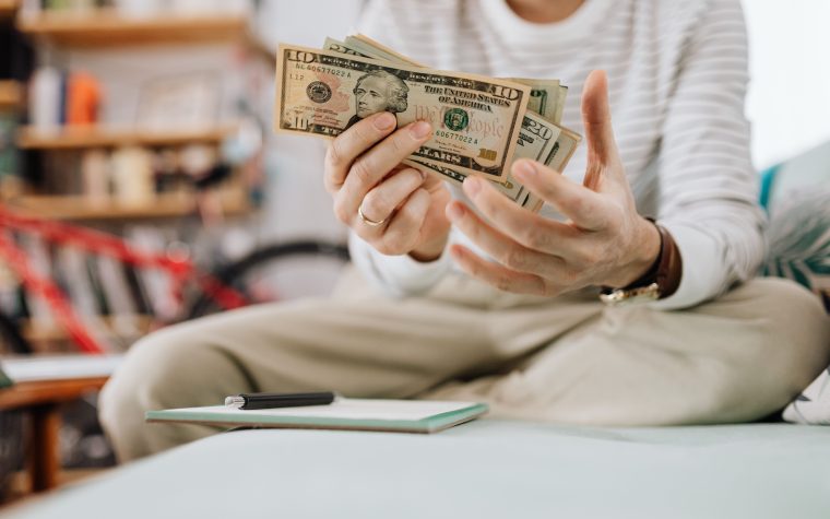 Homme comptant des billets de dollars assis sur canapé